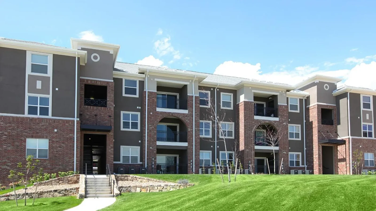 the exterior of an apartment complex with grass and trees at The Outlook Ridge Apartments