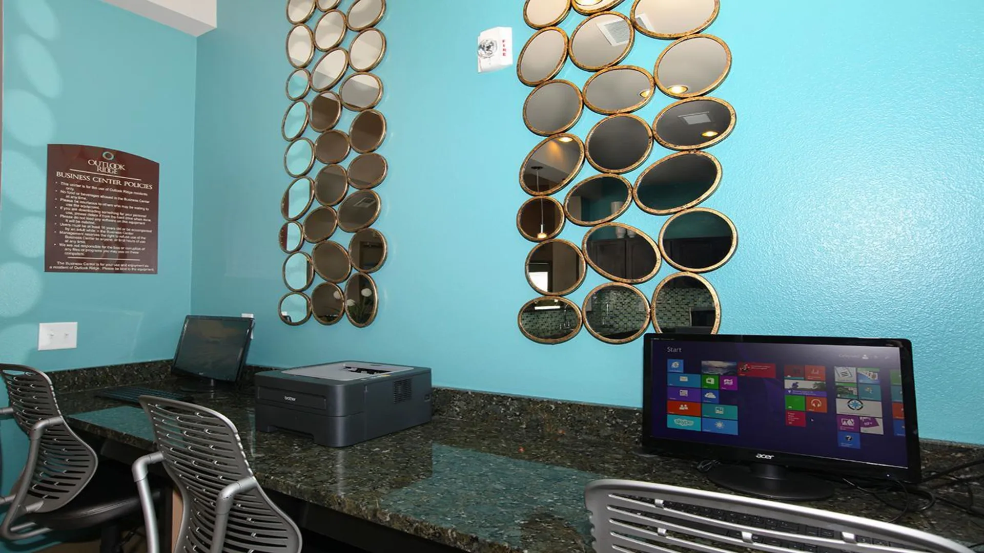 a computer desk with a blue wall and a mirror at The Outlook Ridge Apartments
