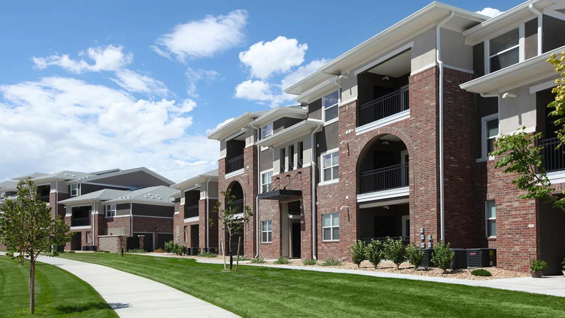 the exterior of an apartment complex with grass and trees at The Outlook Ridge Apartments