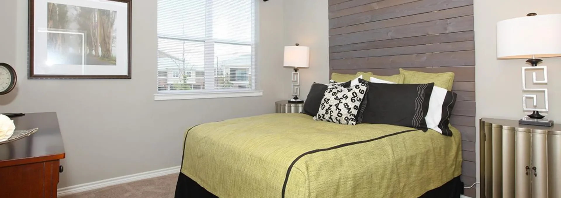 a bedroom with a green bed and black and white accents at The Outlook Ridge Apartments