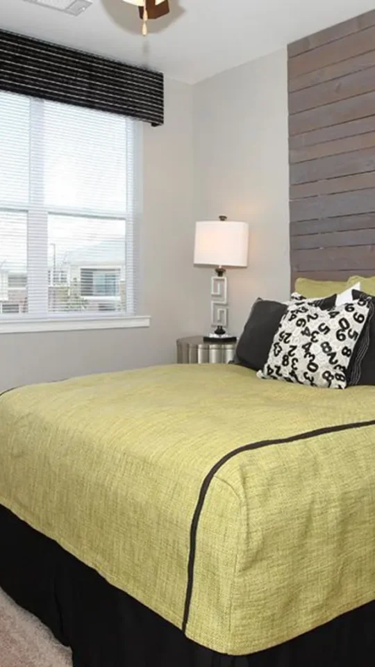 a bedroom with a green bed and black and white accents at The Outlook Ridge Apartments