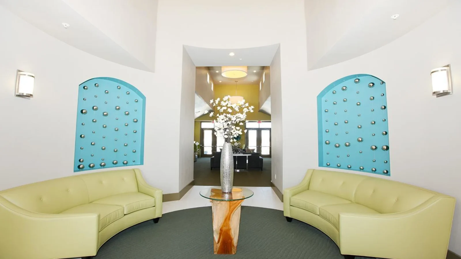 a lobby with a green couch and blue chairs at The Outlook Ridge Apartments