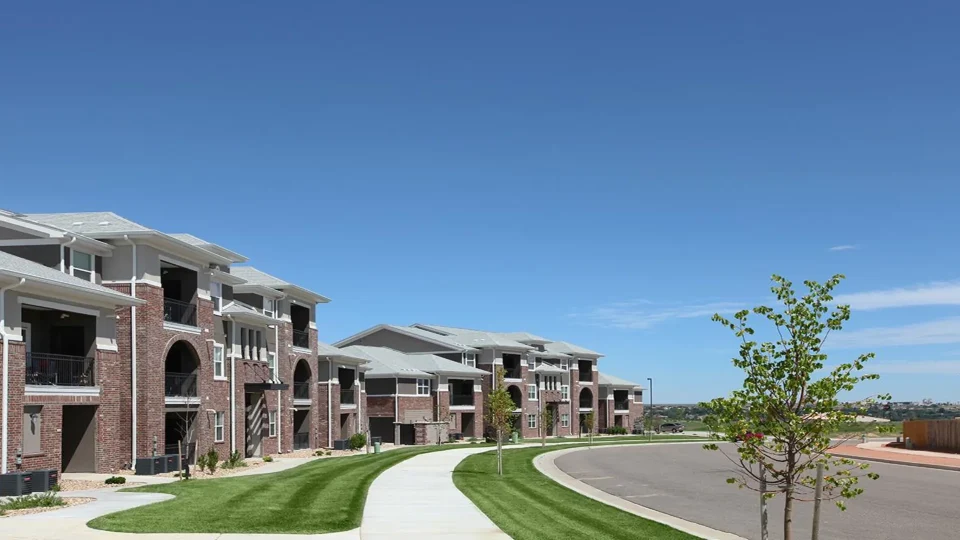 the exterior of a residential complex with landscaping at The Outlook Ridge Apartments