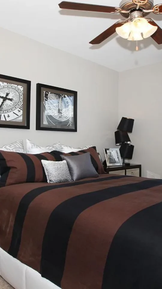 a bedroom with a black and brown bedspread and ceiling fan at The Outlook Ridge Apartments