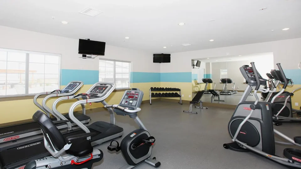 a gym room with tread machines and televisions at The Outlook Ridge Apartments