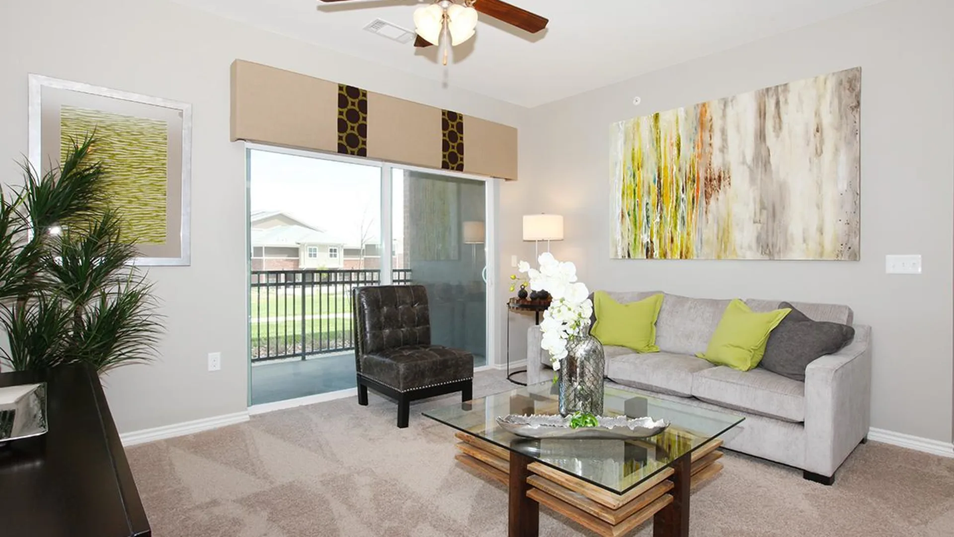 a living room with a large ceiling fan and a large painting at The Outlook Ridge Apartments